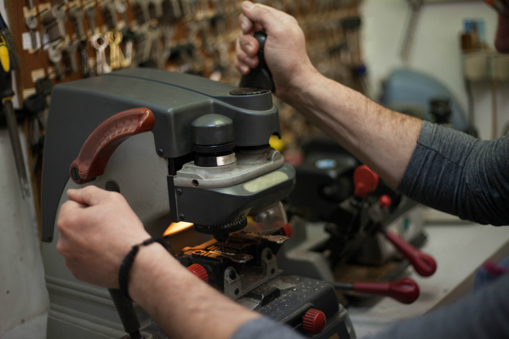 a person operating a milling machine or similar tool in a workshop, with various tools and equipment in the background